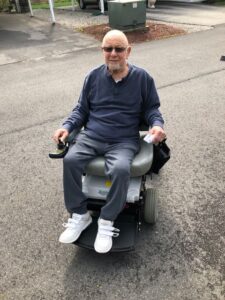 A bald man in an electric wheelchair